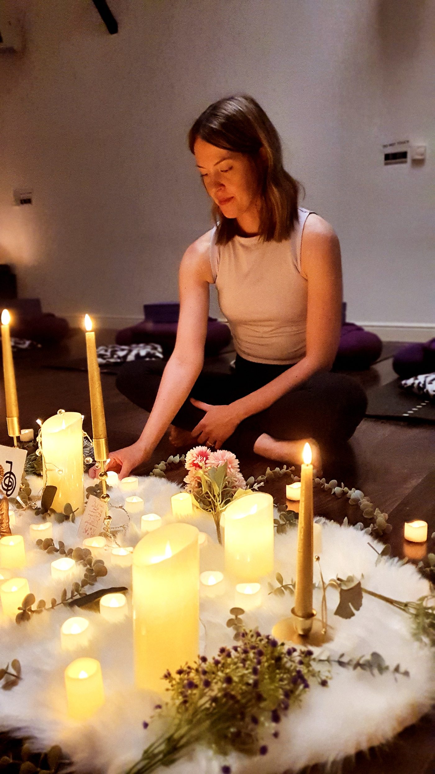 Orla tending the workshop altar — candles and flowers